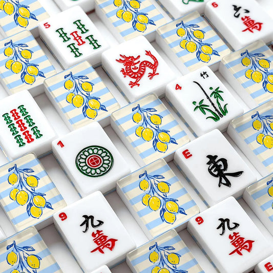 A close-up, top-down view of Mahjong tiles arranged in a grid featuring yellow lemons on light blue striped backgrounds.