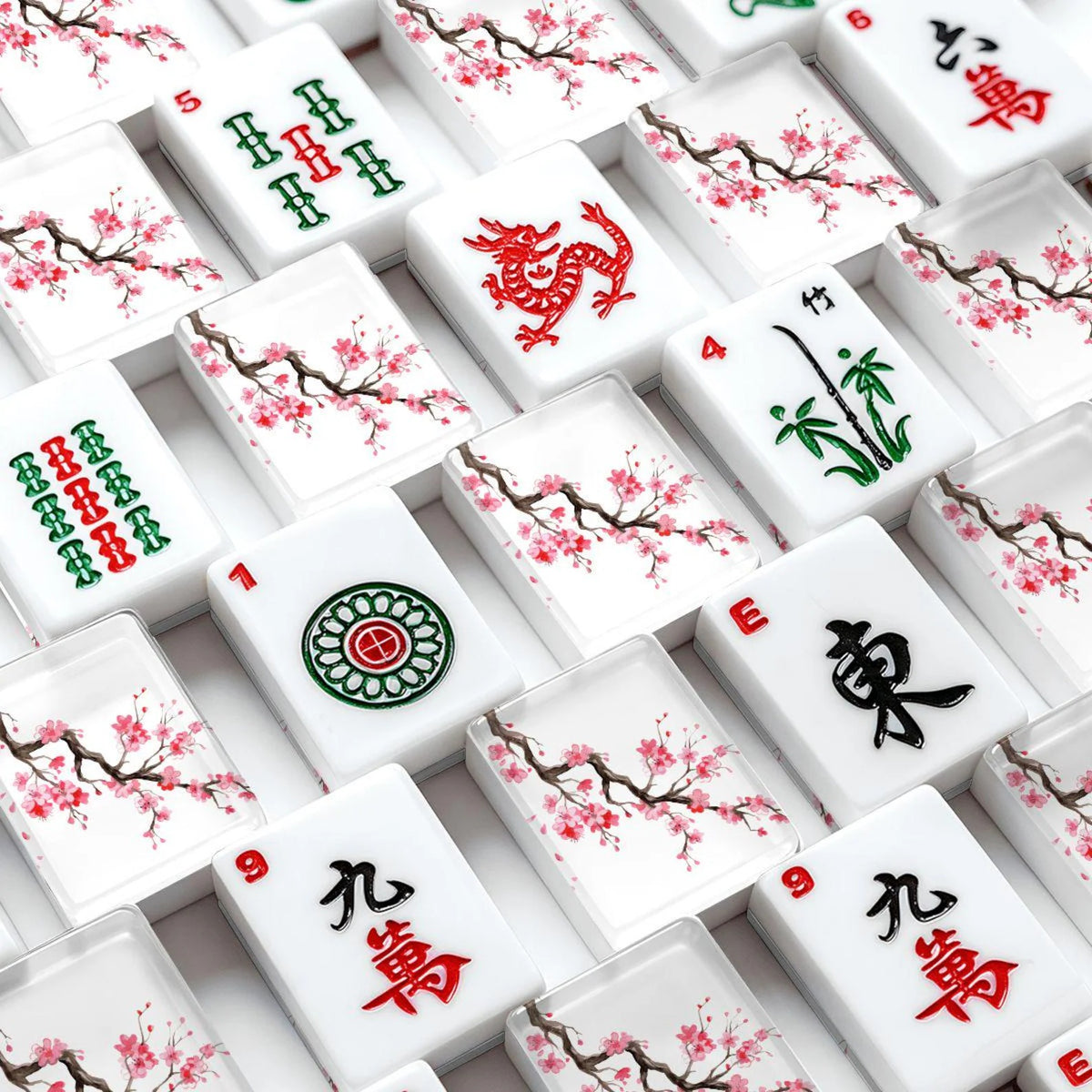 Close-up of a set of white Mahjong tiles with floral cherry blossom designs and traditional Chinese symbols, arranged in a grid pattern.