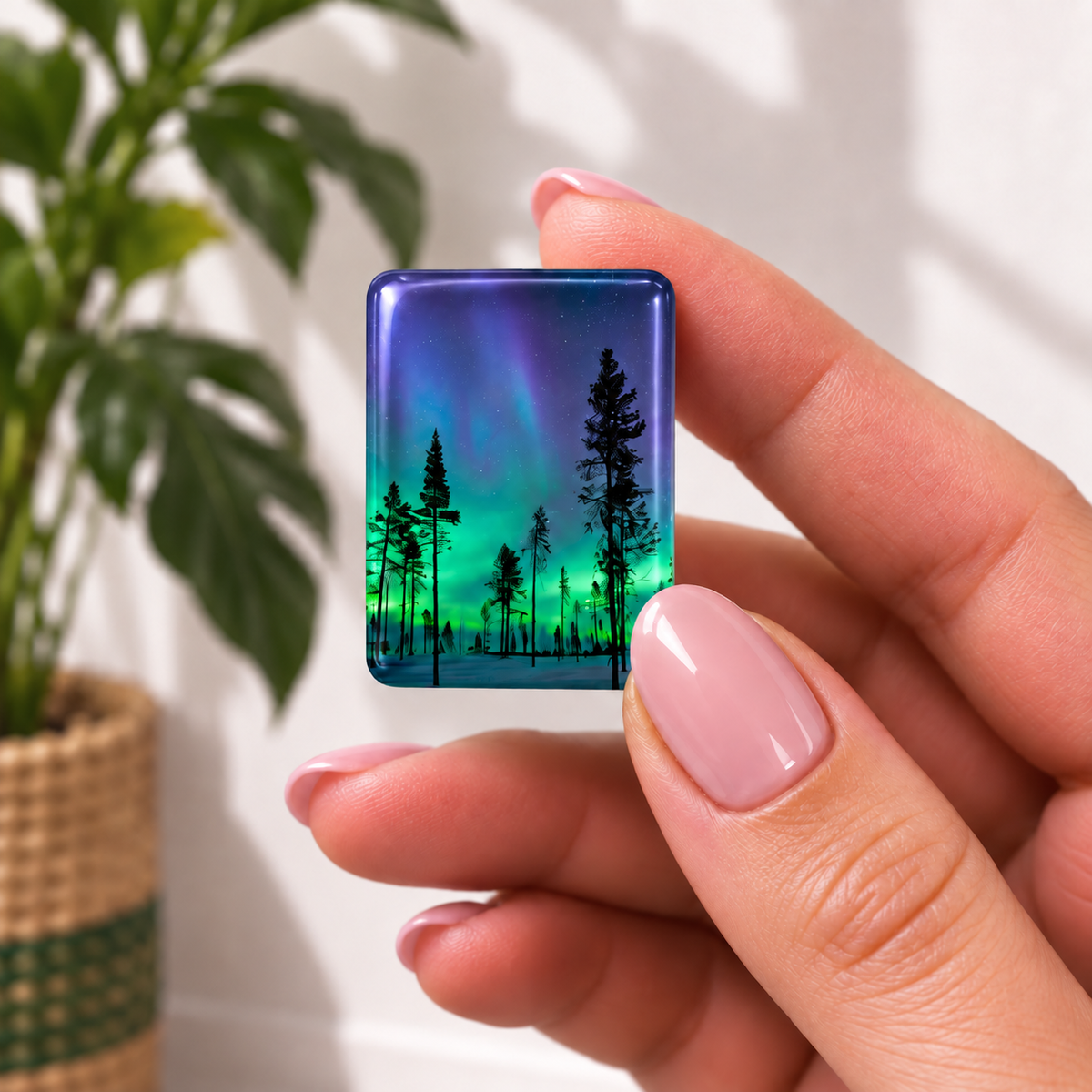 mahjong tile featuring a printed design of silhouetted pine trees against an aurora borealis sky with blue and green hues. 